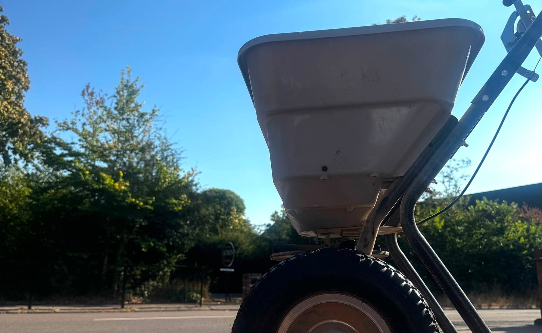 A wheeled spreader used to apply seasonal lawn treatments